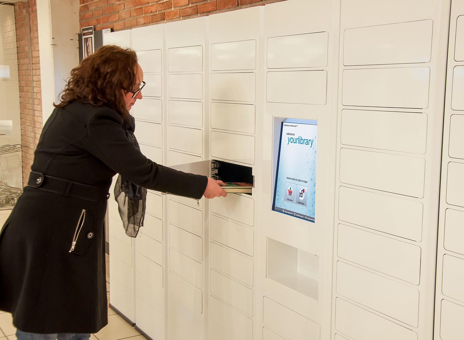 woman grabbing library books from pickup locker