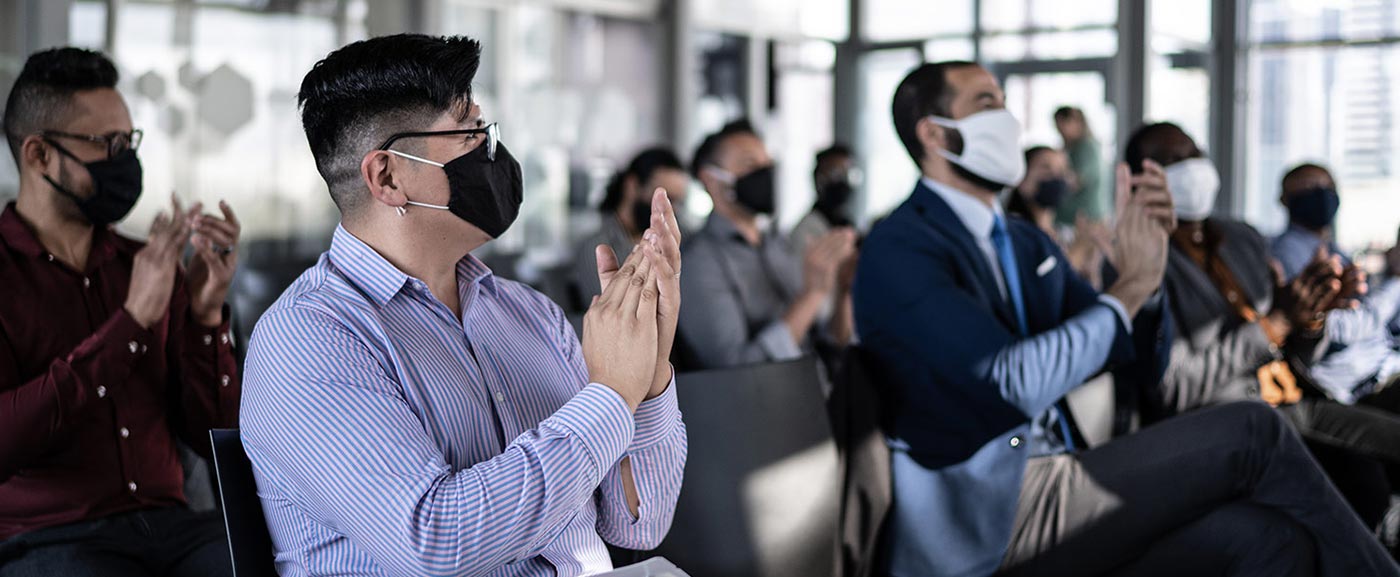 iStock-1260318265 conference audience all clapping wearing masks and socially distanced 1400x577